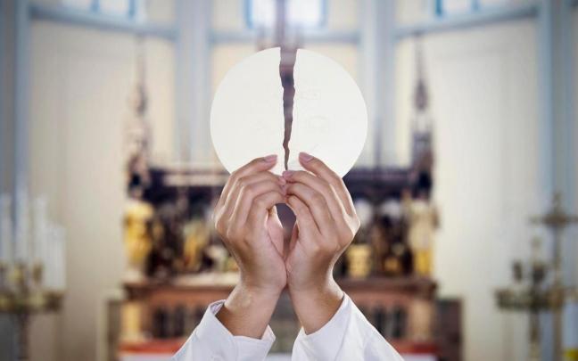 Un sacerdote, consagrando una hostia. Un sacerdote, consagrando una hostia.