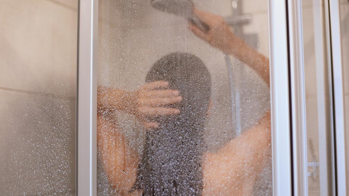 Mampara empañada por el vapor mientras una mujer se ducha.