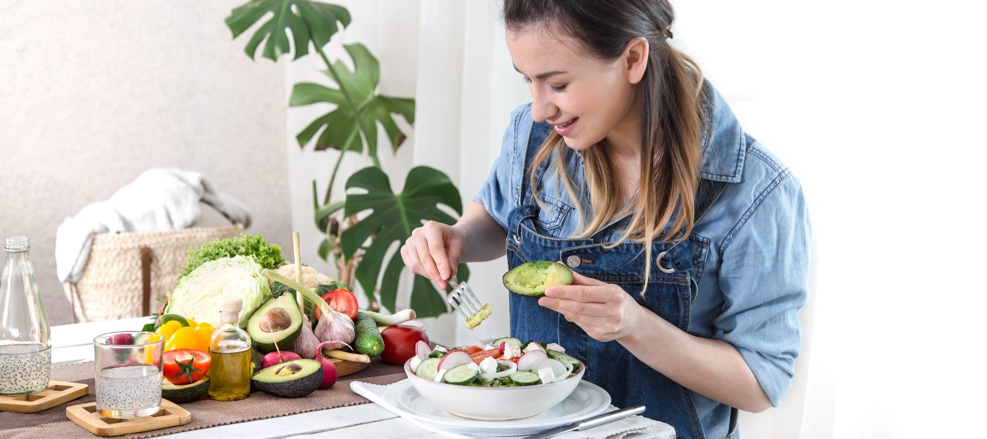 Una joven añade aguacate a una ensalada.